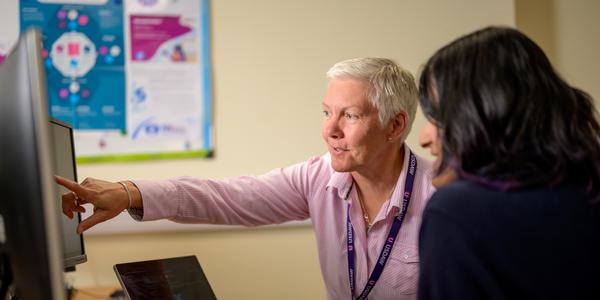 two people with one pointing at computer screen