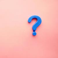 A blue question mark on top of a light pink background