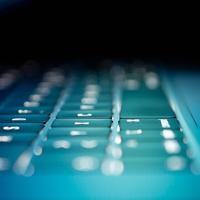 Close up of a laptop keyboard in eerie blue light