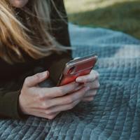 person with long hair holds iphone on a blanket